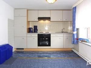 cocina con armarios blancos y lavavajillas negro en Haus Seestern, en Neuharlingersiel