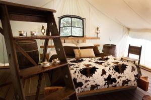 a bedroom with a cow bed in a tent at Domaine Arvor & Spa in Lanvallay