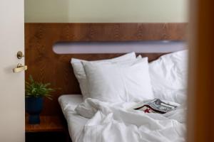 a bed with white sheets and pillows with a book on it at Hotel Soho in Tartu