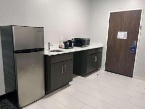 a kitchen with a refrigerator and a sink and a door at Comfort Suites Greenville Airport in Greenville