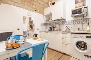 kuchnia z białymi szafkami, stołem i krzesłami w obiekcie La Casuccia Cosy Flat in Old Center w mieście Bari +6 zdjęć