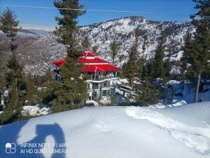 een gebouw met een rood dak in de sneeuw bij Al-Sadiq Hotel & Restaurant Malam Jabba Swat in Swat