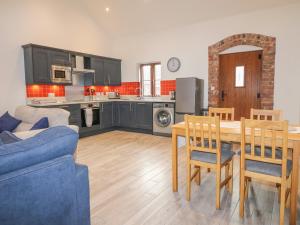 a kitchen and living room with a table and a blue couch at Pipistrelle in Stoke on Trent