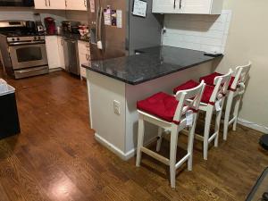 eine Küche mit einer Theke und 4 Hockern mit roten Sitzen in der Unterkunft Perfect near NYC in Newark