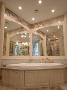 ein großes Bad mit einer großen Badewanne und Spiegeln in der Unterkunft Maison de la riviere in Port-Launay