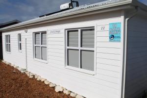 a white shed with windows and a sign on it at Coral Cottage in Struisbaai