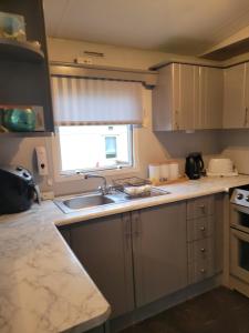 een kleine keuken met een wastafel en een raam bij Cairnryan Heights 2 Bed caravan holiday home in Stranraer
