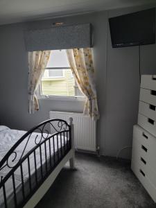a bedroom with a crib and a window with a television at Cairnryan Heights 2 Bed caravan holiday home in Stranraer