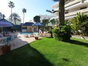 een tuin met stoelen en parasols en een zwembad bij Apartamentos Belmonte in Playa del Inglés