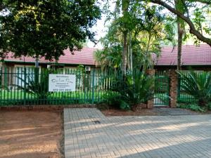 a fence with a sign in front of a building at De la Rose Guesthouse in Lephalale