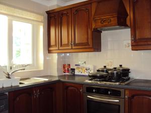 a kitchen with wooden cabinets and a stove with pots and pans at Birchwood Private Room for Homestay in Risley