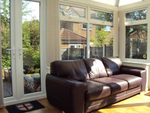 un divano in pelle marrone in una stanza con ampie finestre di Birchwood Private Room for Homestay a Risley Altre 11 foto