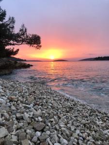 a rocky shore with the sun setting over the water at Villa Nature Forever in Maslinica