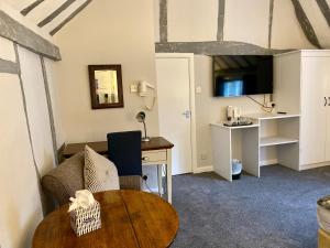 a room with a table and a desk and a tv at White Hart Hotel in Dorchester on Thames