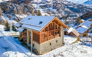 a log cabin in the snow with mountains in the background at L'Or des Cimes in Valloire