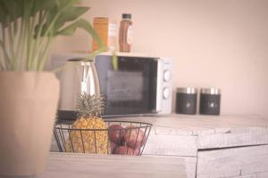 a pineapple in a basket on a counter next to a microwave at Lovely 1-bedroom Garden Cottage in Klerksdorp