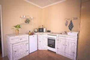 a kitchen with white cabinets and a white refrigerator at Lovely 1-bedroom Garden Cottage in Klerksdorp