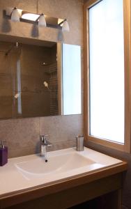 a bathroom sink with a mirror and a window at La tour Bocsozel in La Côte-Saint-André