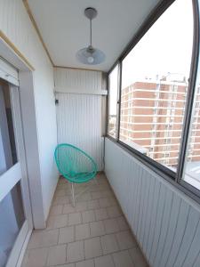 Cette chambre dispose de fenêtres et d'un balcon avec une chaise verte. dans l'établissement Departamento de 3 dormitorios completamente equipado, à Bahía Blanca