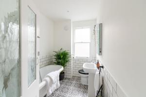 a bathroom with a tub and a toilet and a sink at Doghouse Margate in Kent