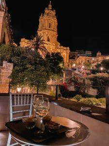 a table with a glass of wine sitting on top of a city at San Giorgio Modica Hotel in Modica