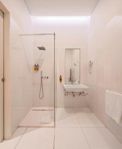 uma casa de banho branca com um chuveiro e um lavatório. em Lisbon Serviced Apartments - Estrela em Lisboa