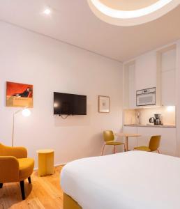 a bedroom with a bed and chairs and a tv at Lisbon Serviced Apartments - Estrela in Lisbon
