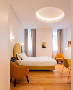 um quarto de hotel com uma cama e duas cadeiras em Lisbon Serviced Apartments - Estrela em Lisboa