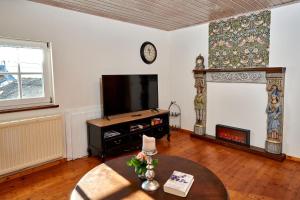 ein Wohnzimmer mit einem TV und einem Kamin in der Unterkunft Ritterstube - Eifelstuben mit Charme, Nähe See und Burg, außergewöhnlich, Vulkaneifel in Ulmen