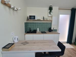 a kitchen with a table and a green tile wall at Le Petit Roche in Roche-la-Molière