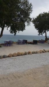 un grupo de mesas y bancos en una playa en Camping Paleochora, en Palaiochóra