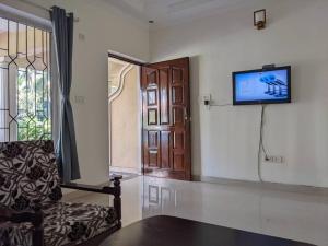 a living room with a couch and a tv on the wall at Tangerine Stay - Friends & Family 4BHK Villa, Goa in Dabolim