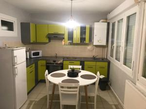 a kitchen with green cabinets and a table with chairs at Le bien venue chez vous in Calais