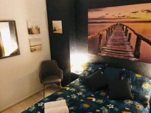 een slaapkamer met een bed en een schilderij van een pier bij Le bien venue chez vous in Calais
