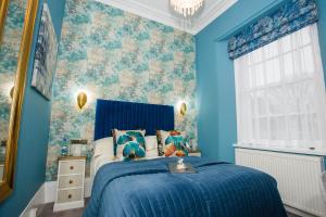 1 dormitorio con paredes azules y 1 cama con colcha azul en The Cleveland, en Torquay