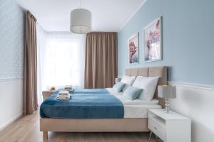 a bedroom with a large bed with a blue blanket at Symphony Modern Tower Aparthotel in Gdynia