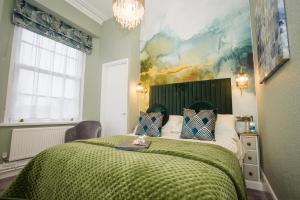 a bedroom with a large bed with a green blanket at The Cleveland in Torquay