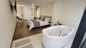 - une chambre avec une baignoire et un lit dans l'établissement Hotel Piedras De Maní, à Manizales