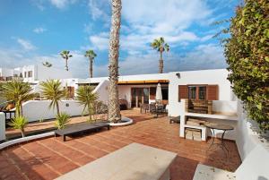 patio z palmami i białym domem w obiekcie Puerto Chico 3 w mieście Playa Blanca