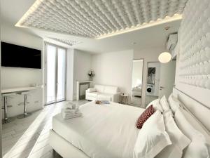 a white bedroom with a large bed and a tv at Mariarosa Suites in Como