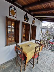 a table and chairs on a patio with a table and windows at Archontiko Elena in Volos