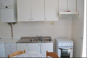 eine Küche mit weißen Schränken, einer Spüle und einem Tisch in der Unterkunft Appartamento 5 in Ameglia