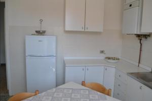 a white kitchen with a table and a refrigerator at Appartamento 5 in Ameglia +2 photos
