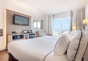 a hotel room with a white bed and a television at Melia Sitges in Sitges