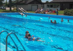 a group of people swimming in a swimming pool at Ätrans Stugby & Fritidsanläggning in Ätran
