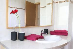 a bathroom sink with a vase with a red flower at Gutenberg - helle und geräumige Wohnung in Uninähe in Mainz +25 photos