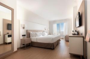 a white bedroom with a large bed and a mirror at Melia Sitges in Sitges
