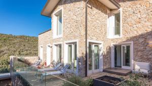 kamienny dom ze szklanym balkonem z krzesłami w obiekcie VILLA LE MANDRIE 7&2, Emma Villas w mieście Castiglione della Pescaia