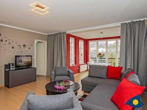 Villa Lucie Else Whg 08 في هيرينجسدورف: غرفة معيشة مع أريكة وتلفزيون