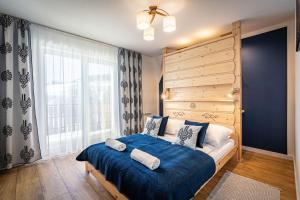 a bedroom with a bed with blue sheets and a large window at Aparteo Apartament Pod Wierchem in Kościelisko